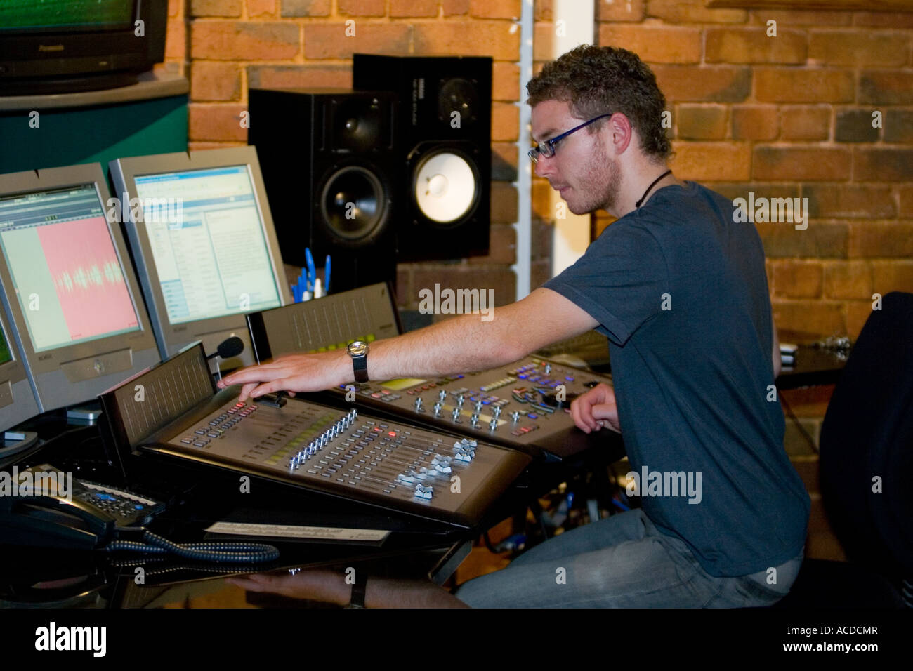 young man mixing at sound desk console mixer in recording studio Stock