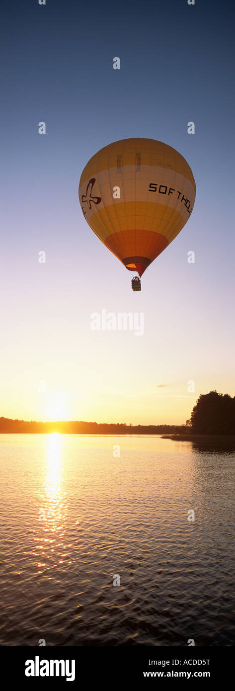 A hot air balloon flying over calm water in sunset Stock Photo - Alamy