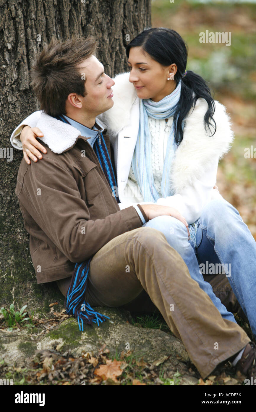A young couple is sitting on the ground in the autumn forest lifestyle ...