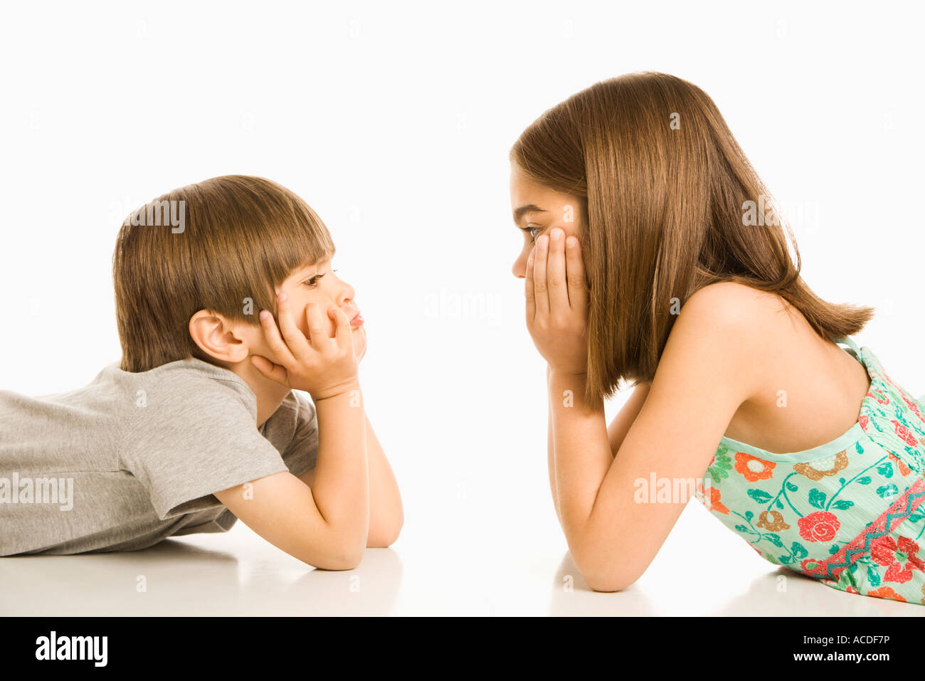 Portrait of girl and boy lying looking at eachother Stock Photo - Alamy