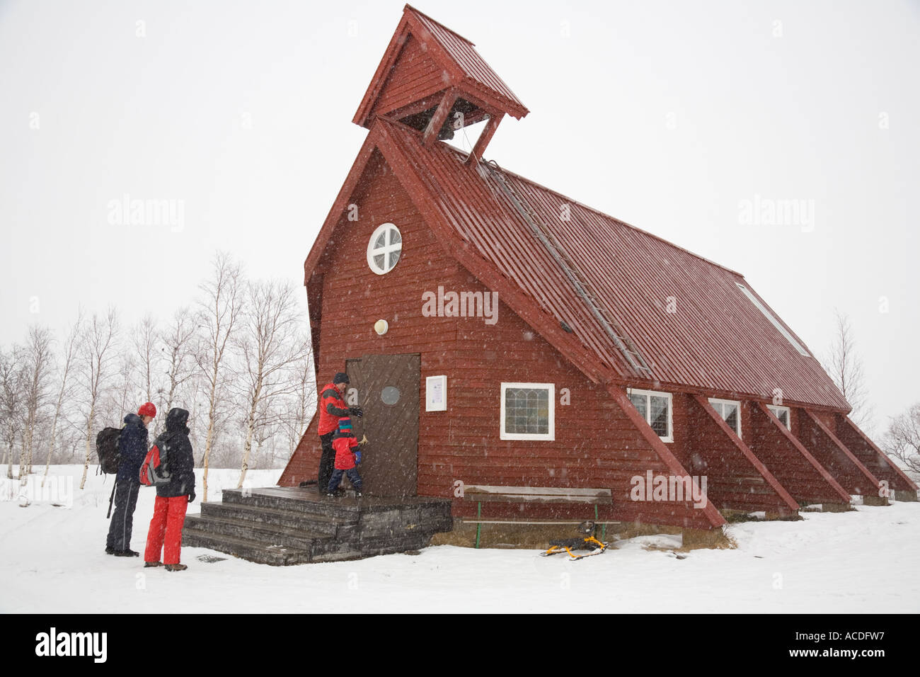 Kiruna (Northern Sweden): Visitors standing in front of the Nikkaluokta church in blowing snow Stock Photo