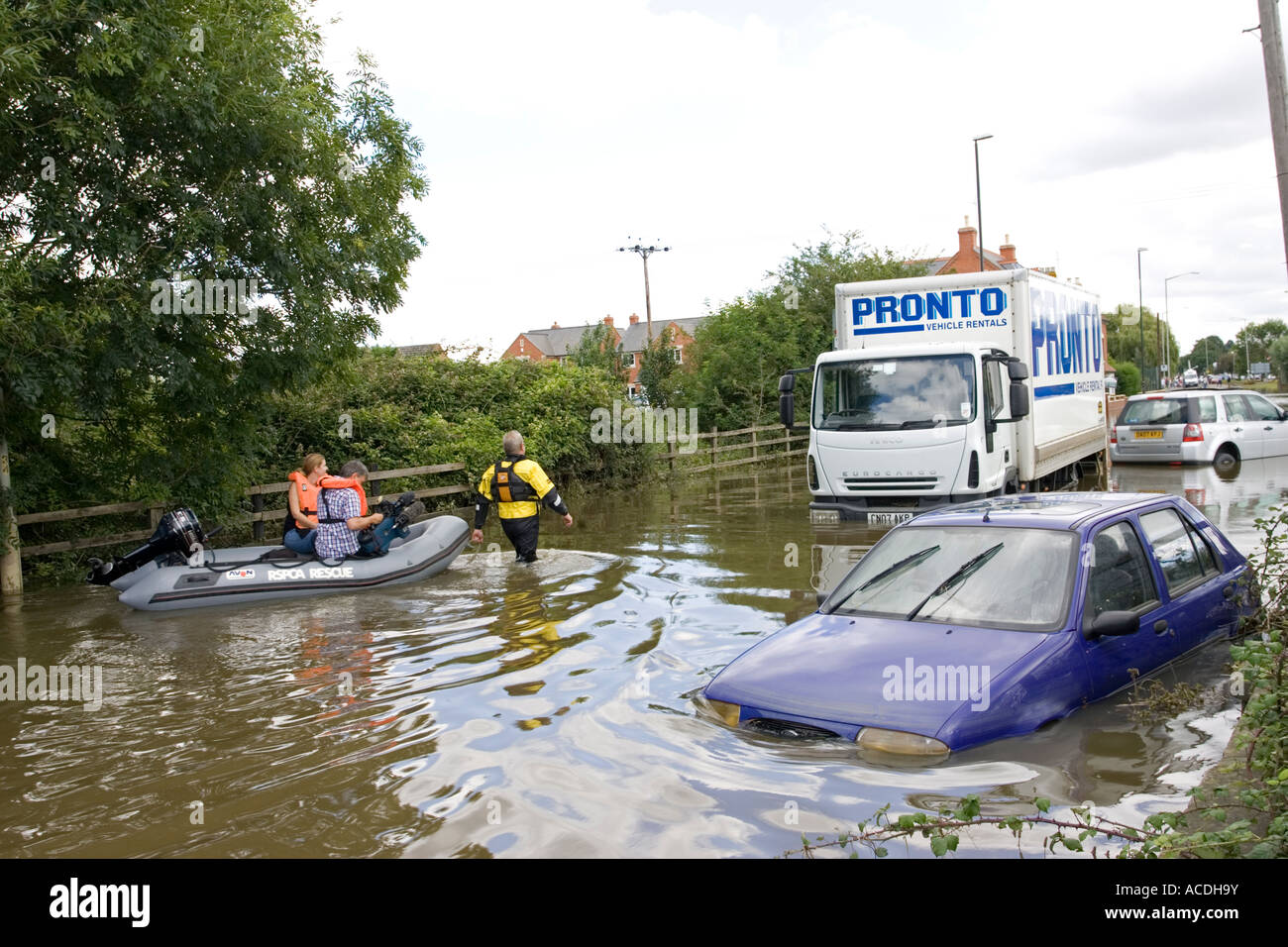 Rescue workers taking people in inflatable dingy along flooded with ...