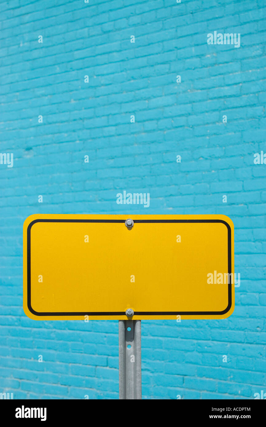 Blank yellow sign in front of blue exterior wall Stock Photo - Alamy