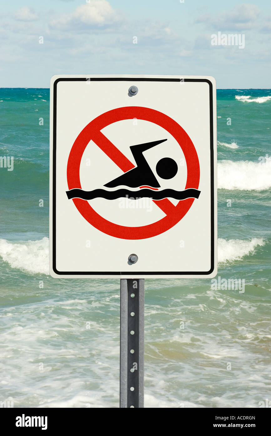 Swimming not allowed sign with rough surf in background Stock Photo