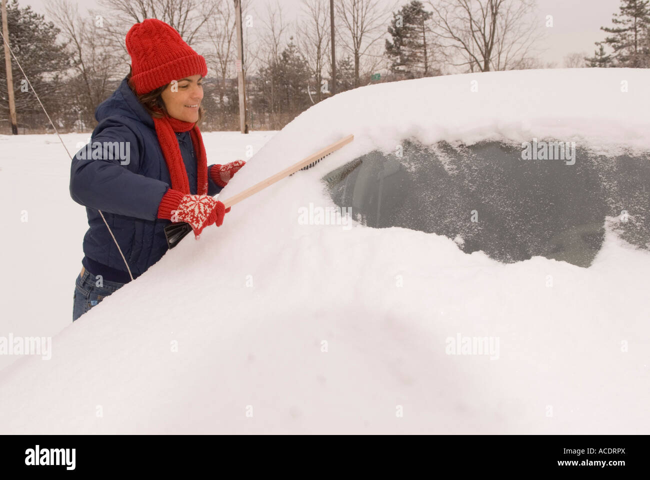 Woman brushing snow off car windshield (windscreen), Ann Arbor, Michigan, USA Stock Photo