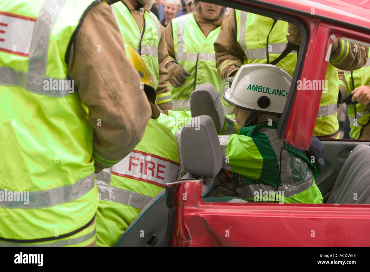 Ambulance paramedic treat a car crash victim from within the car whilst firemen cut the roof off