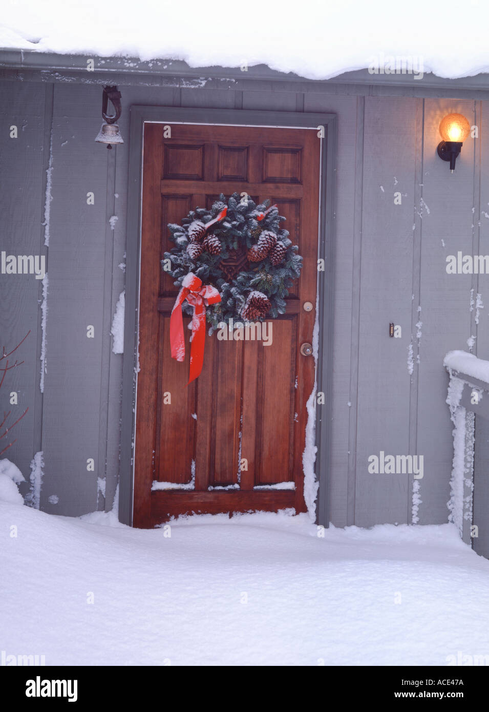 Christmas wreath on front door of suburban home with new snow covering the deck Stock Photo