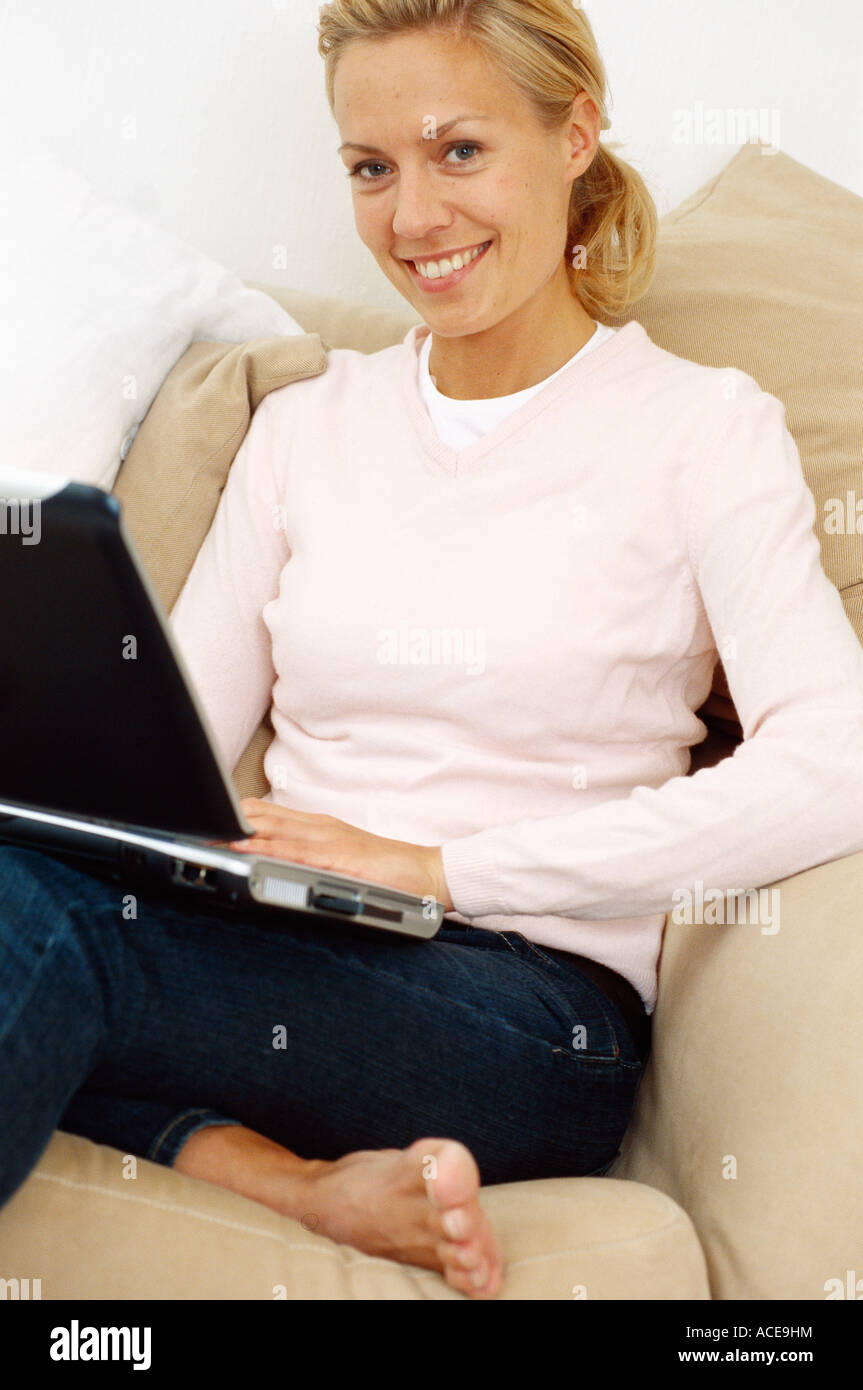 A smiling woman with a laptop in a sofa Stock Photo - Alamy