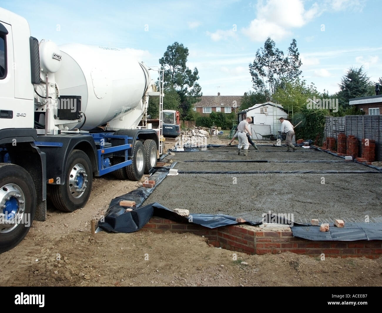 Concrete delivery truck and men placing concrete into ground floor