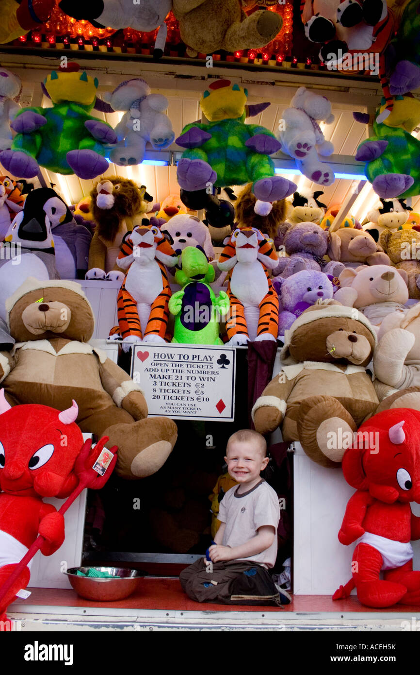 Small child surrounded by soft toys on a fairground stall, Ireland