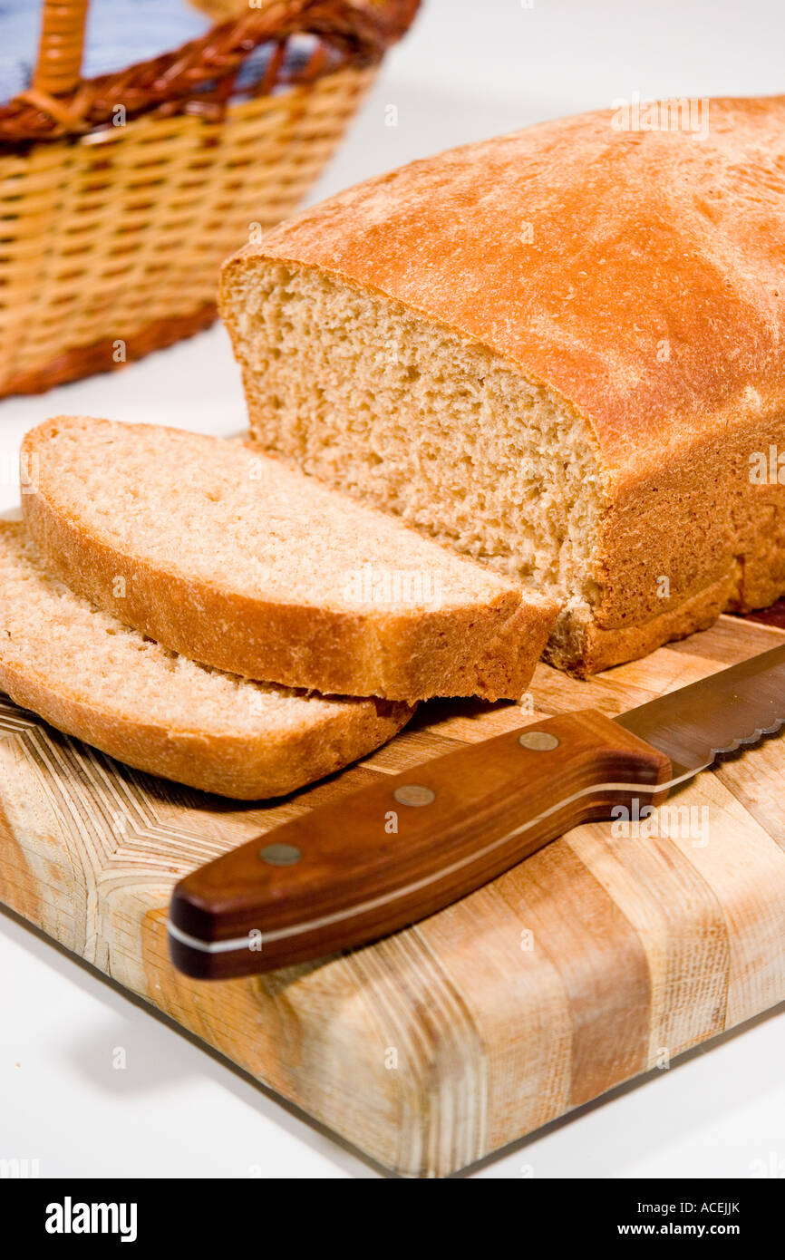 A loaf of freshly baked whole wheat bread sliced on a wood cutting ...