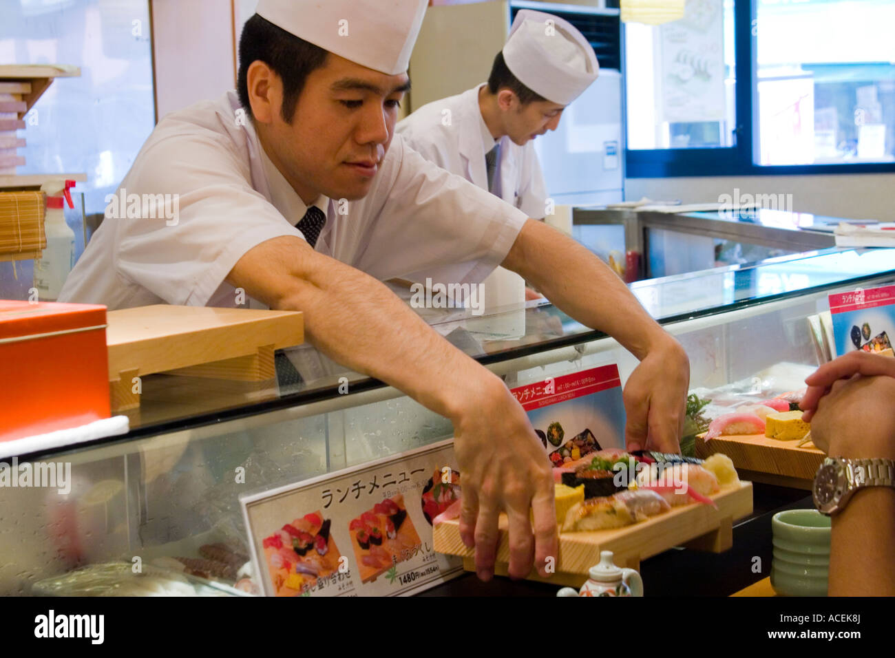 Sushi chef serving a geta tray of sushi to a customer at the counter of a Japanese sushi restaurant Tokyo Japan Stock Photo