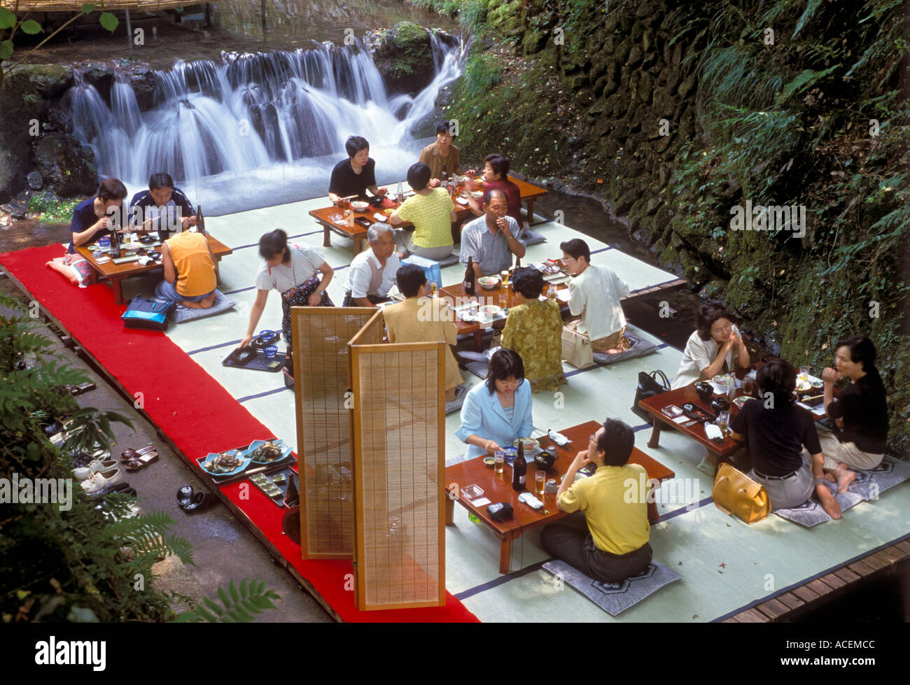 During hot summer months people enjoy natural breeze while having lunch on platforms erected over mountain stream Stock Photo