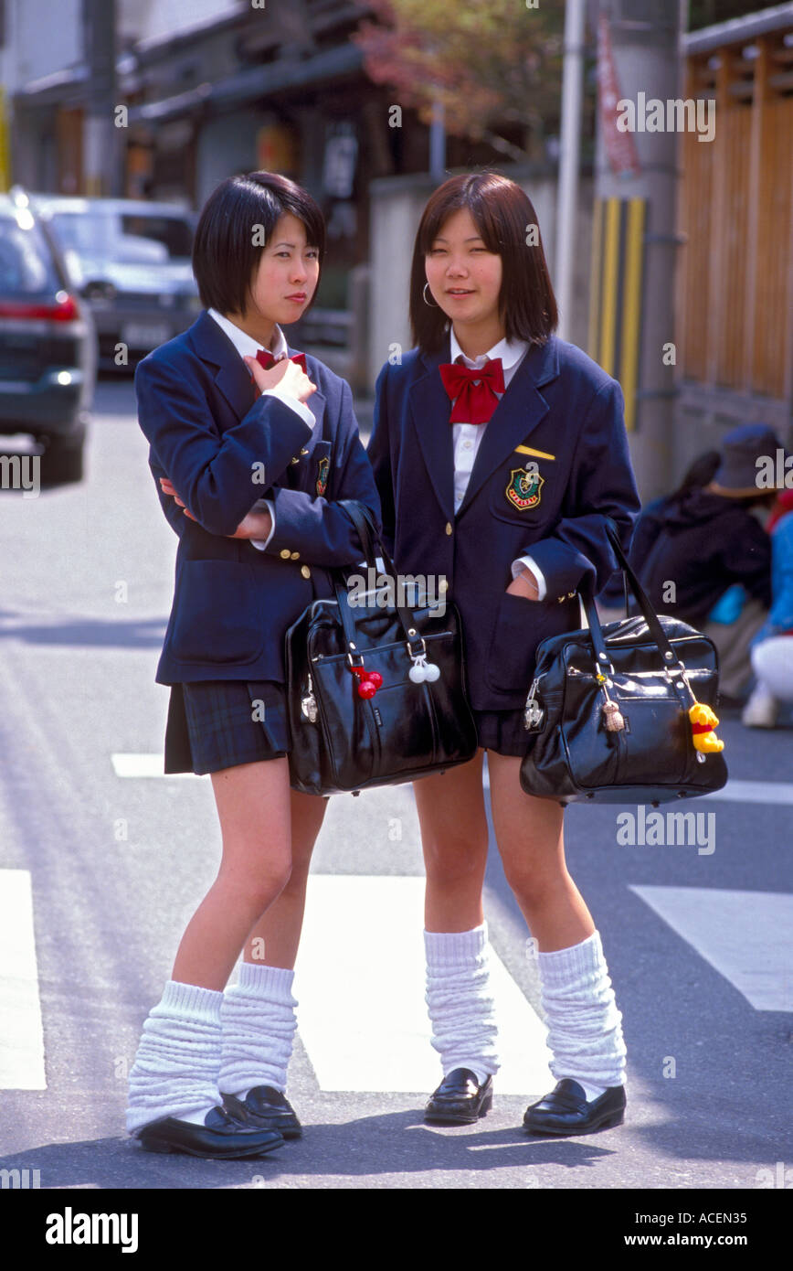 Two high school girls in uniform stand on the street chatting Stock Photo
