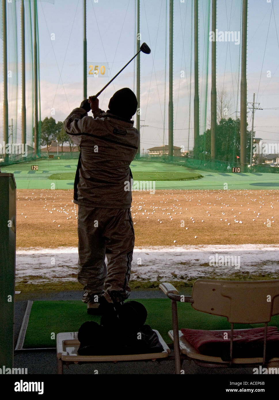 Man takes a swing at a golf ball at a practice driving range in Japan