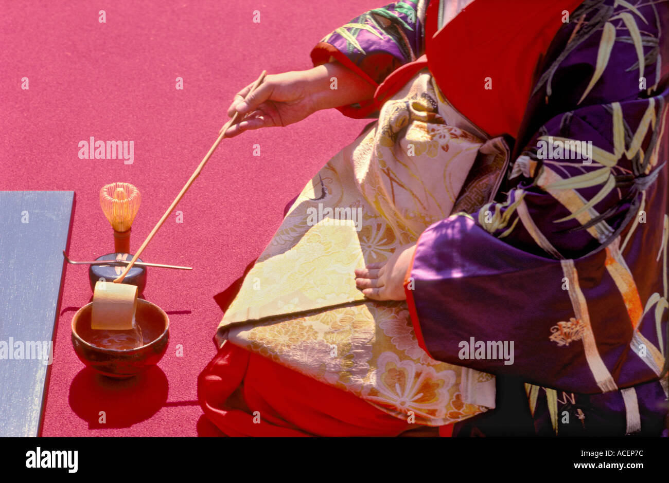 A woman in kimono pours hot water into a chawan cup with a bamboo hishaku ladle during a Japanese tea ceremony in Japan. Stock Photo