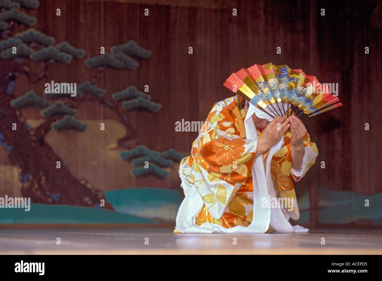 Performer In Traditional Noh Costume Holding Fan Executes A Move During A Kyogen Play Stock Performer In Traditional Noh Costume Holding Fan Executes A Move During A Kyogen Play Stock