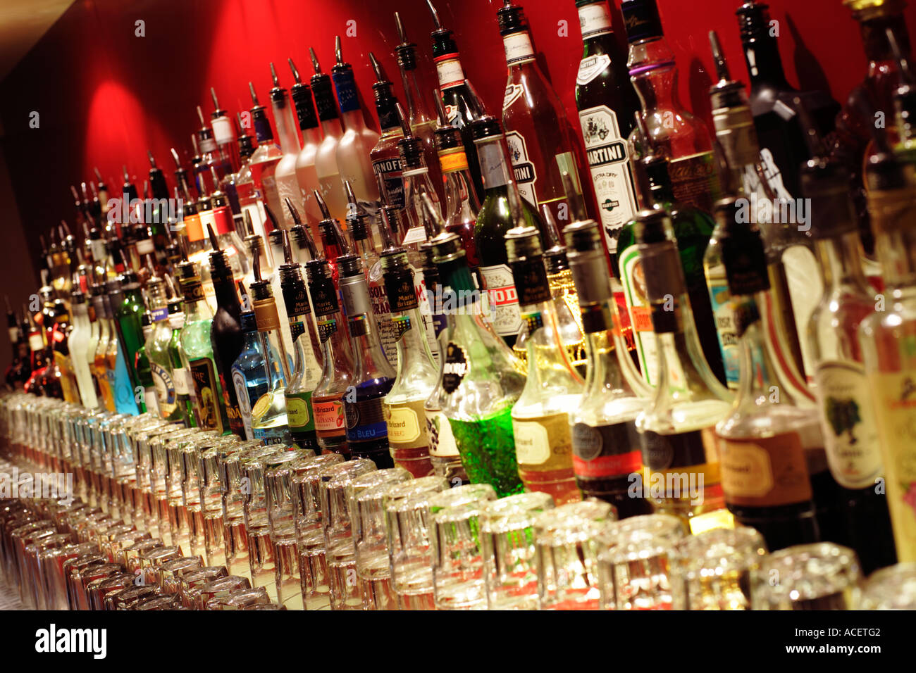 Row of alcoholic drink bottles and spirits behind a bar with glasses Stock Photo