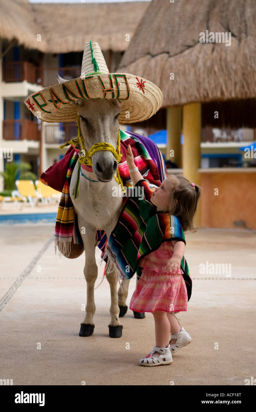 Little girl petting a donkey dressed in 