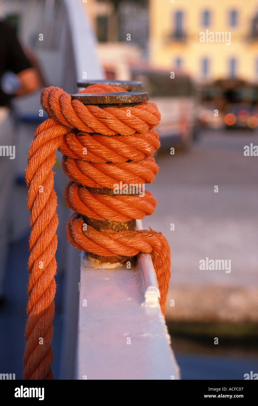 thick weathered orange rope coiled and tied to mooring post on boat rail  securing ship Stock Photo - Alamy