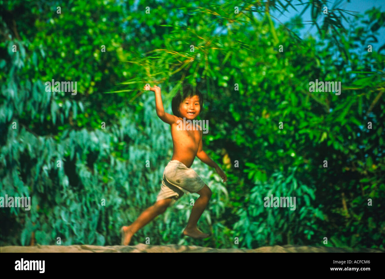 Vietnam Mekong Delta boy friendly waving from dike | Vietnam Mekong Delta, kleiner Junge winkt froehlich vom Deich Stock Photo