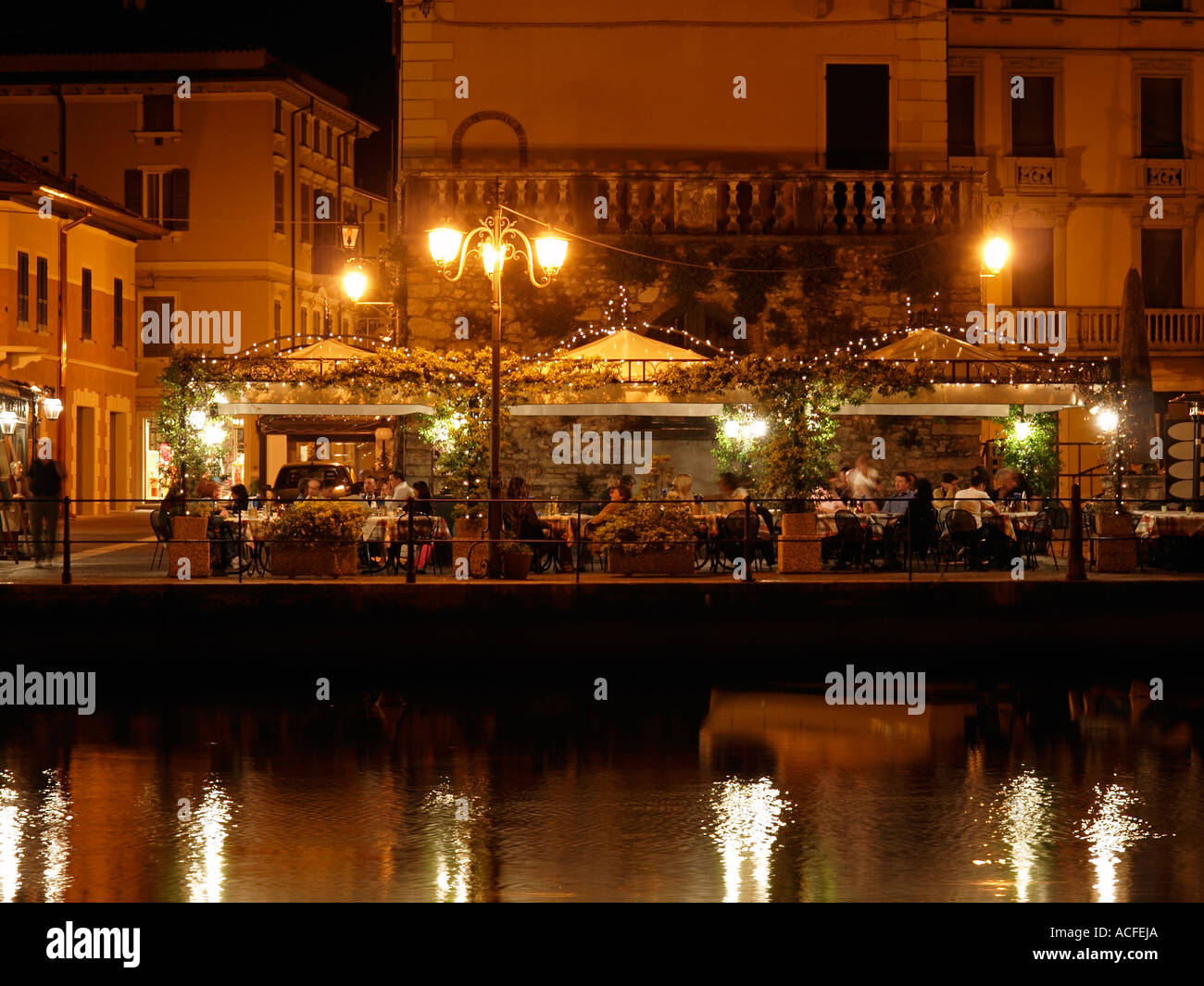People dining outside after dark at a restaurant in Peschiera del Garda Garda lake Italy Stock Photo