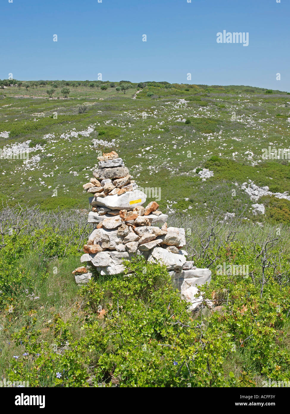 dry landscape without trees and shadow Garrique with a pile of stones as sign for right way hiking track Stock Photo