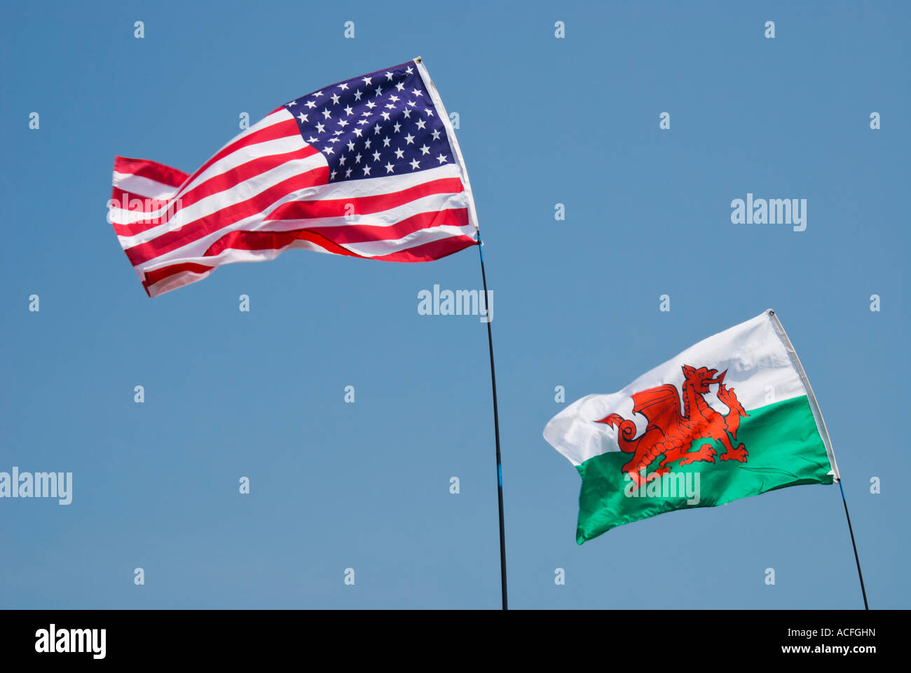 American and Welsh flags flying together on a blue sky background Stock