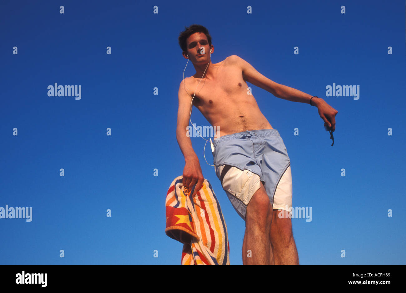 Tall, thin young German man balancing on a post listening to music on his  ipod Stock Photo - Alamy