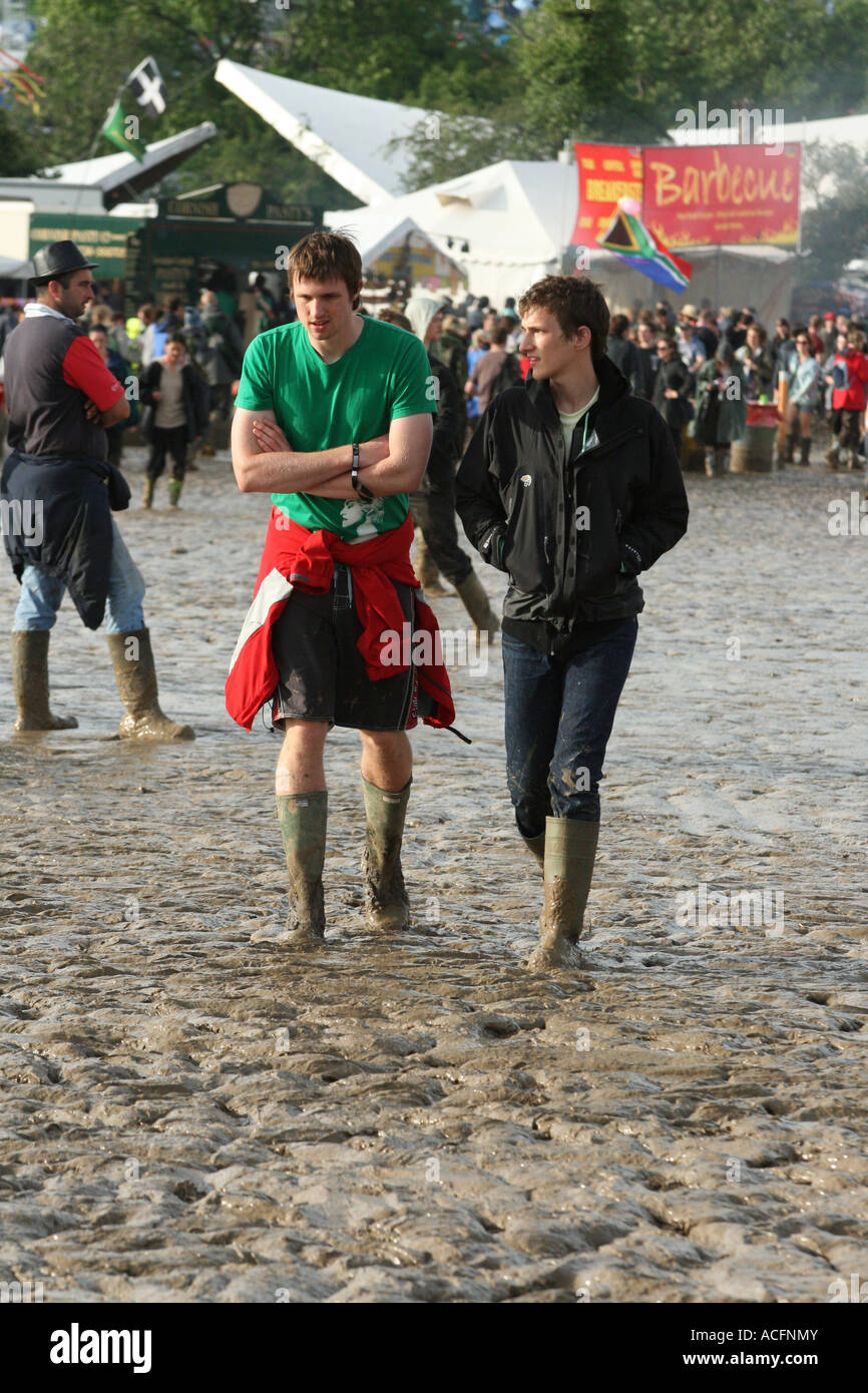 Two guys walking through a field of mud in the market area of the Glastonbury festival 2007. Stock Photo