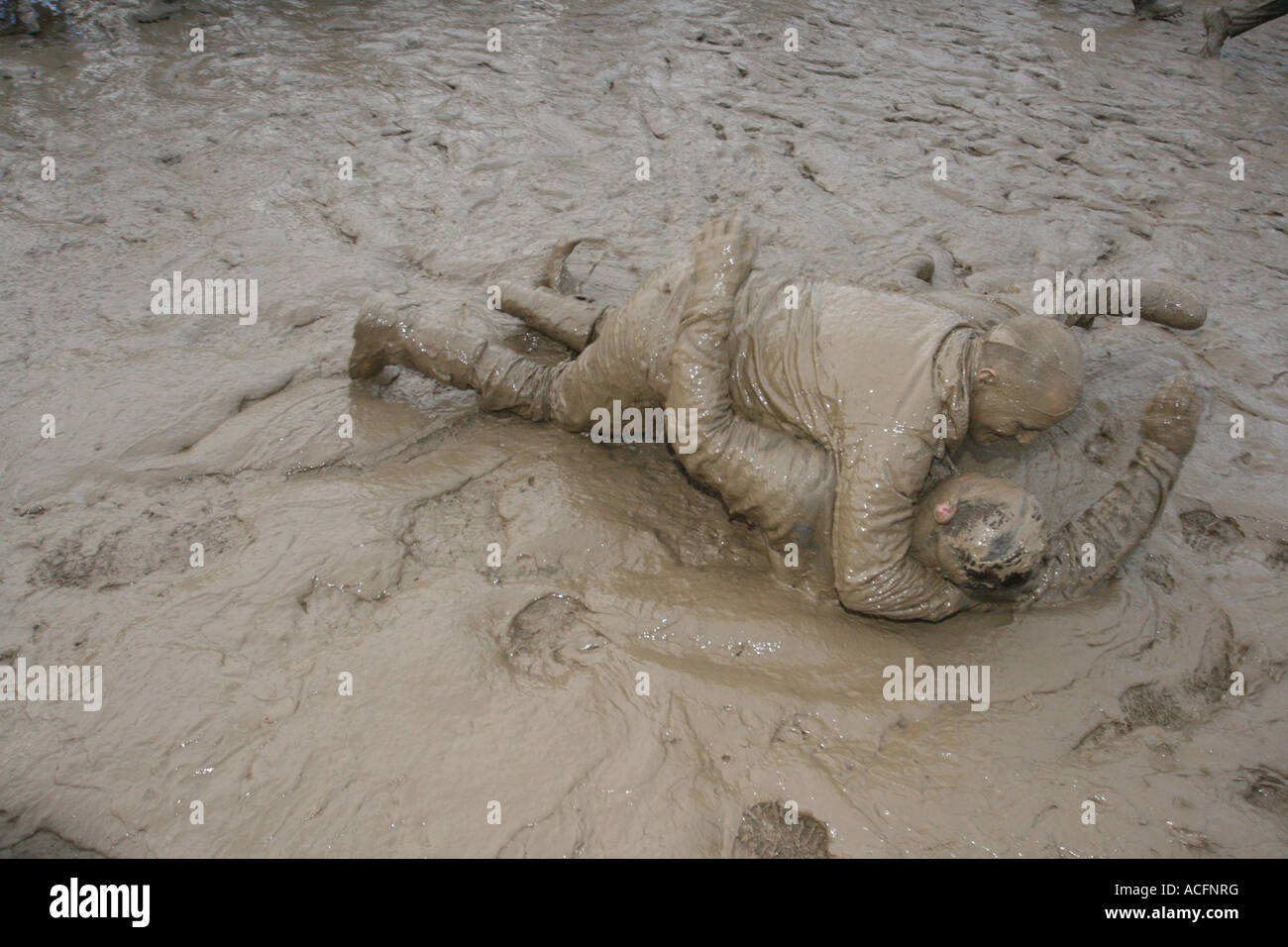 Mud monsters, Two excited young men wrestling in the Mud at the Glastonbury Festival 2007. Stock Photo