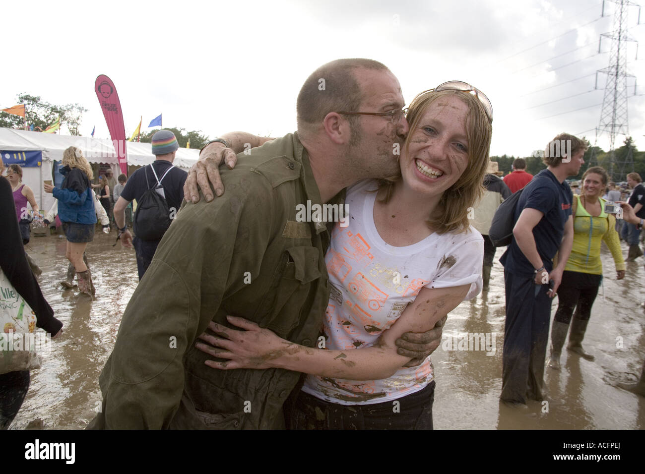 A man with his face covered in mud kissing a smiling woman at the Glastonbury Festival 2007. Stock Photo