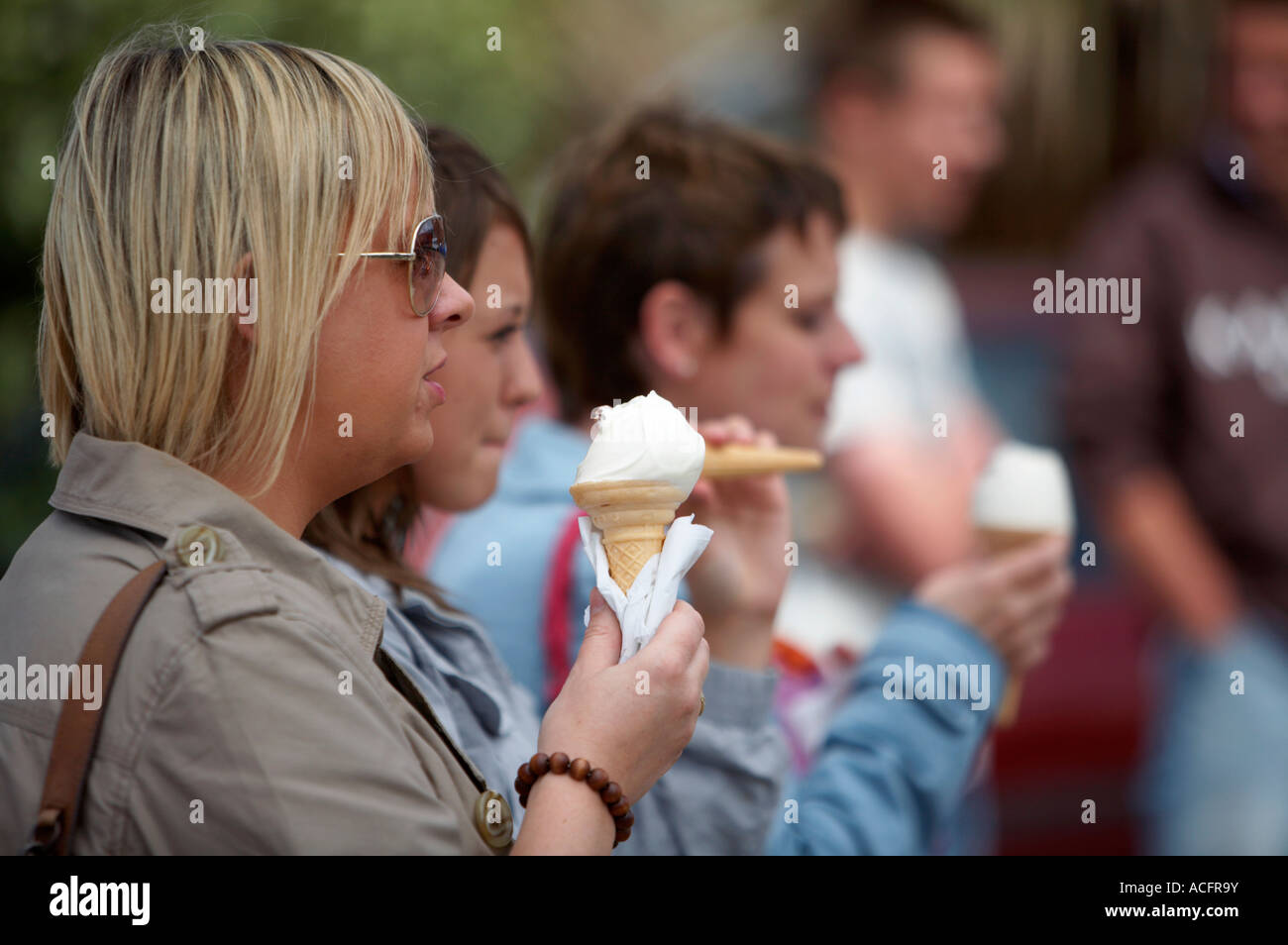 three young irish women eating ice cream cones looking right Stock