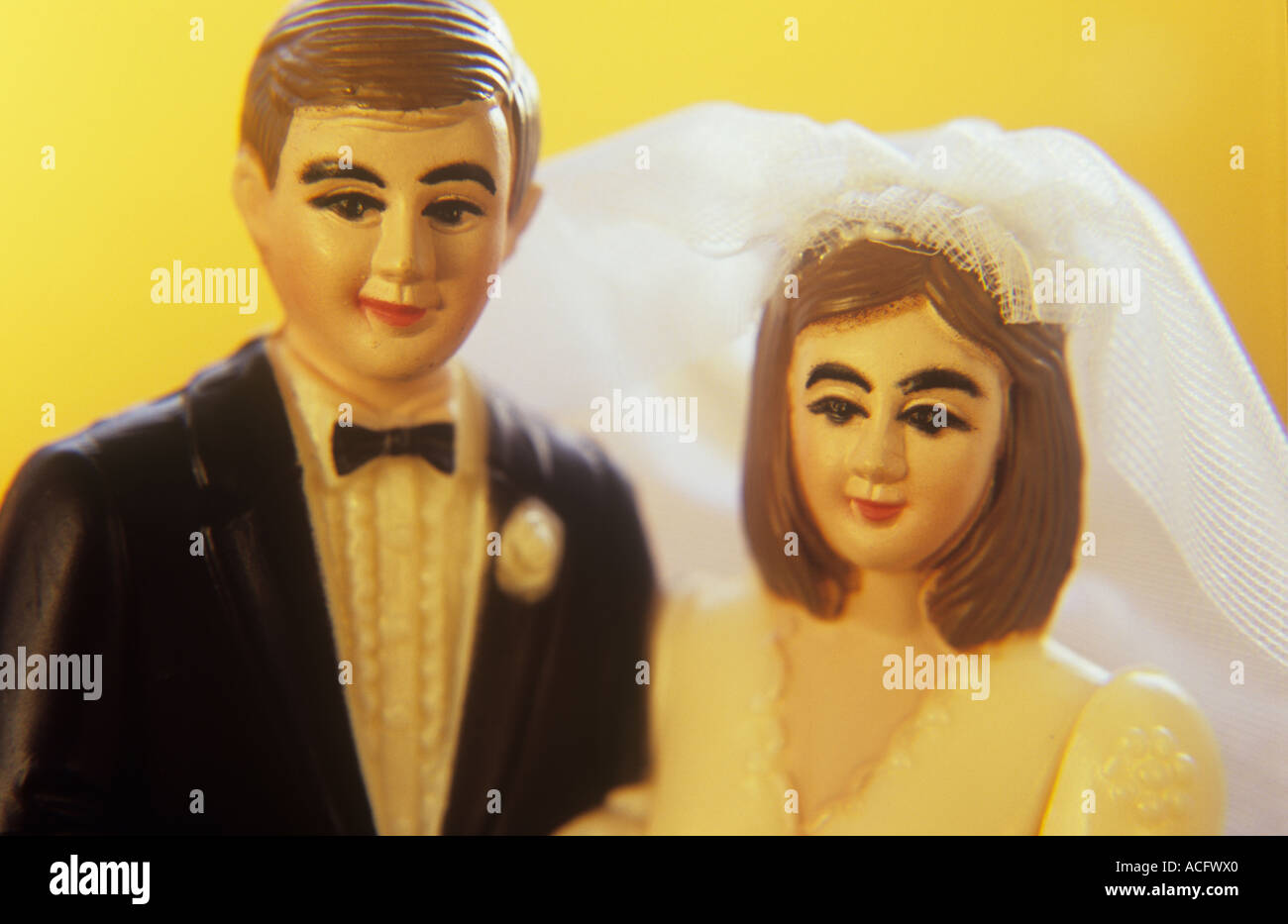 Close up in warm golden light of a plastic miniature model of a man and woman in full wedding attire getting married Stock Photo