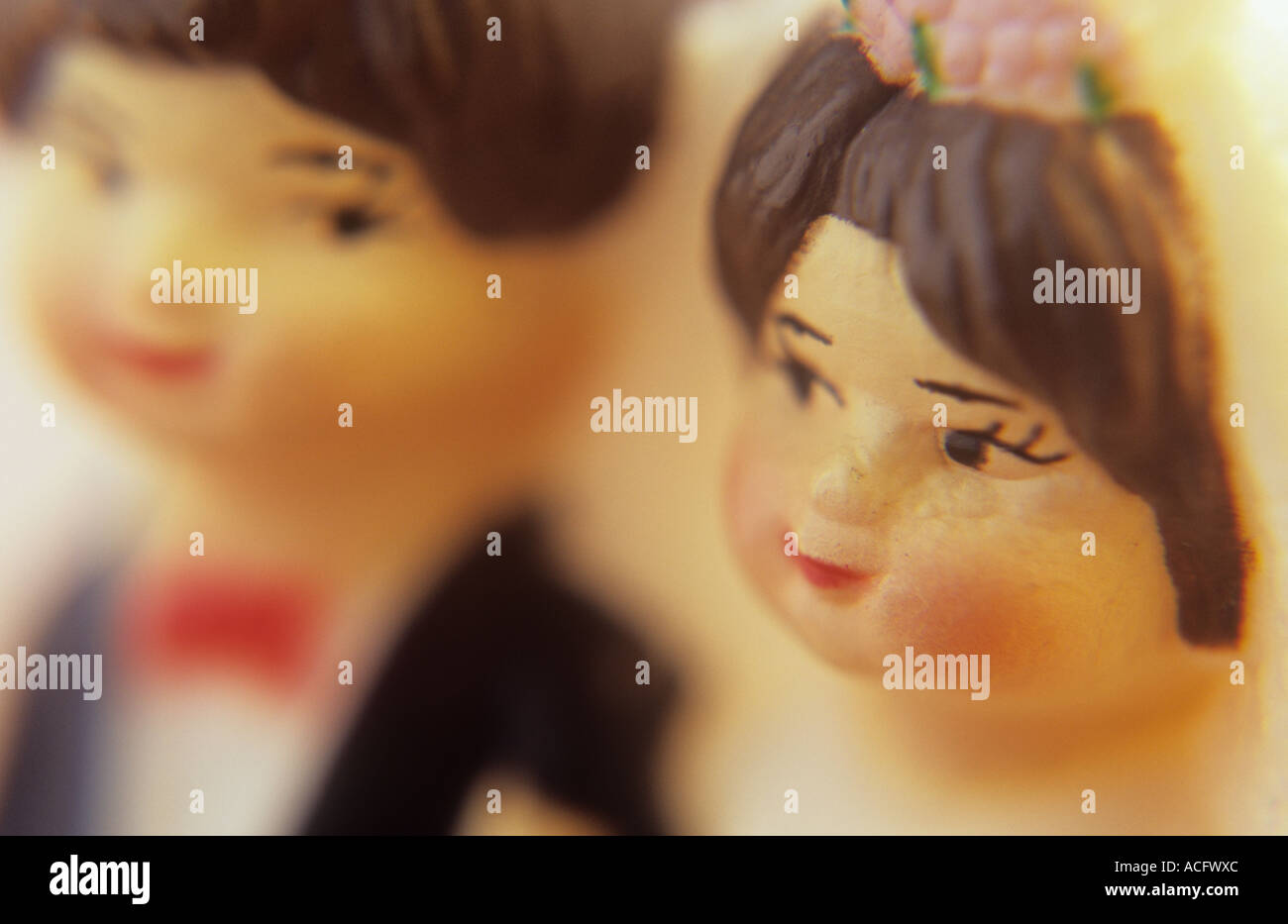 Close up in warm golden light of a plastic miniature model of a man and woman in full wedding attire getting married Stock Photo