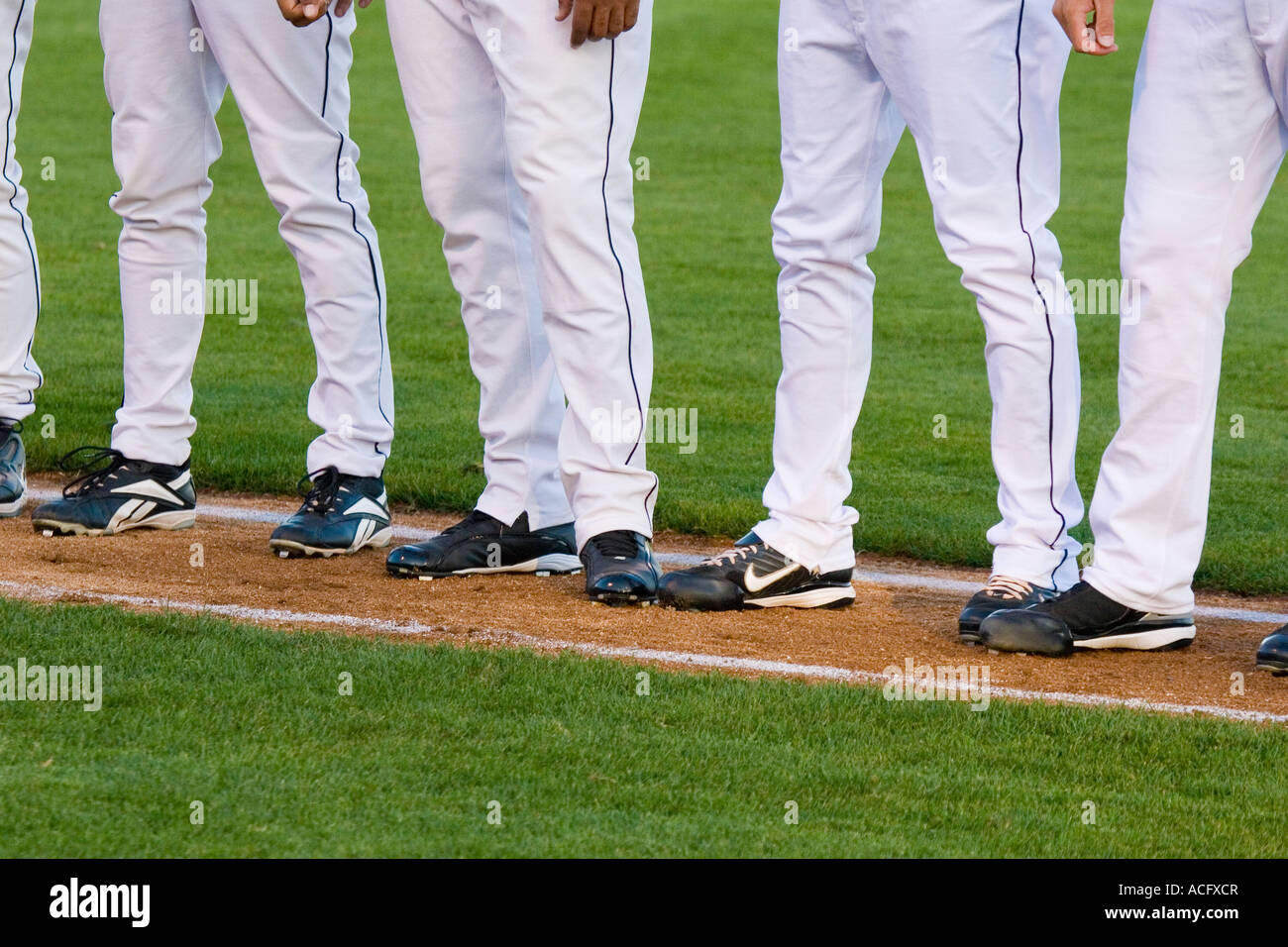 Legs of professional baseball players standing in a row along the first