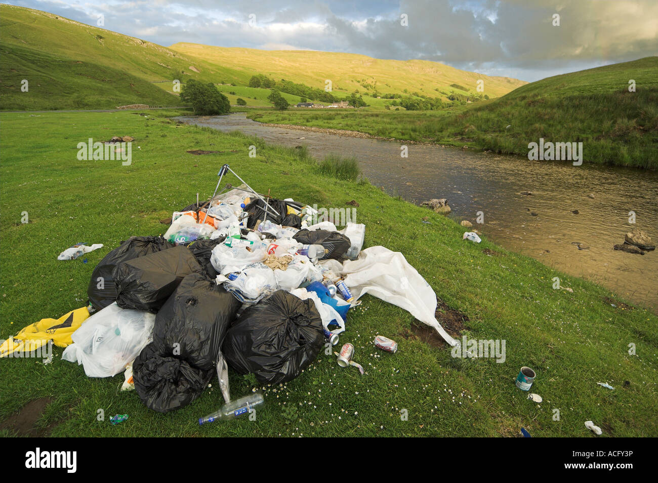 Fly tipping in the countryside leaving rubbish against the River Eden Cumbria Stock Photo