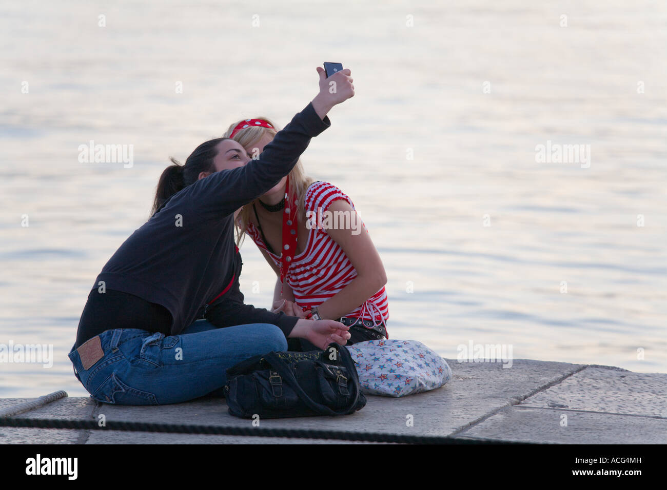 Girlfriends teen teenagers girls taking pictures of each other using cellular phone Stock Photo