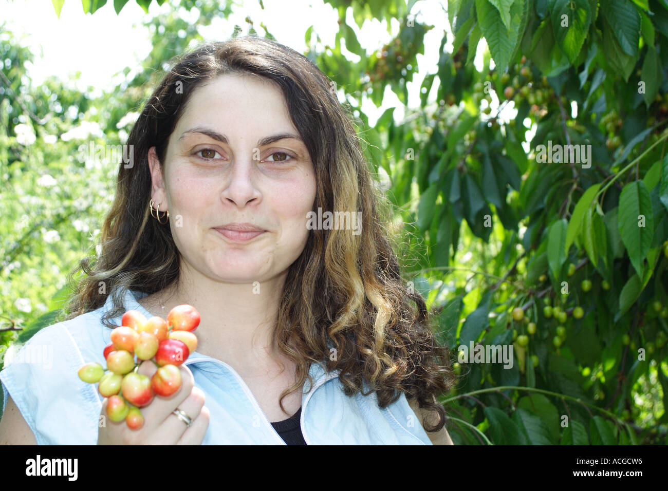 Young woman smiling and holding bunch of cherry Stock Photo