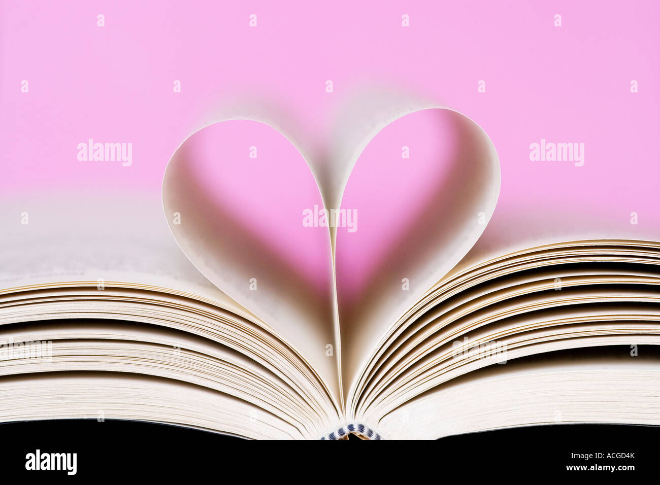 Heart shape made from book pages against a pink background Stock Photo