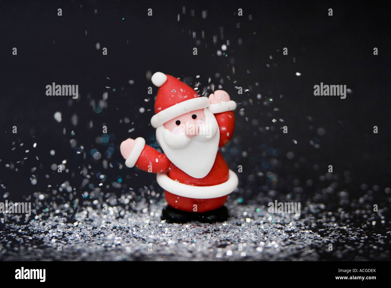 Father Christmas decoration against black surrounded by glitter Stock Photo