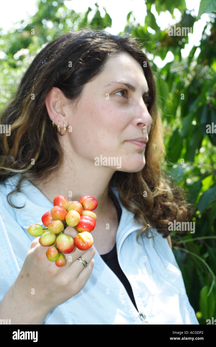 Young woman smiling and holding bunch of cherry Stock Photo