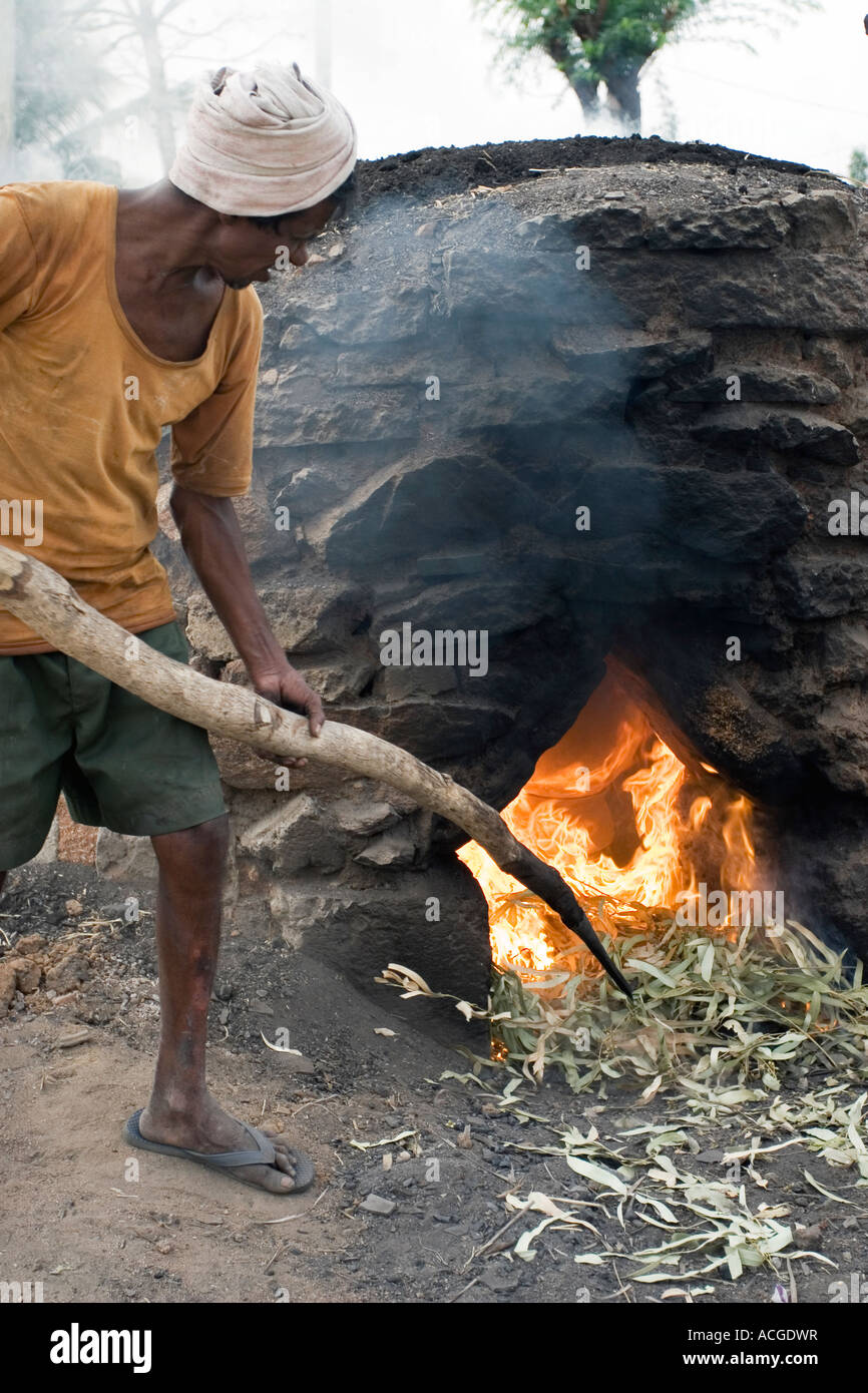 Indian man firing clay pots in an outside kiln in the town of Puttaparthi, Andhra pradesh, India Stock Photo