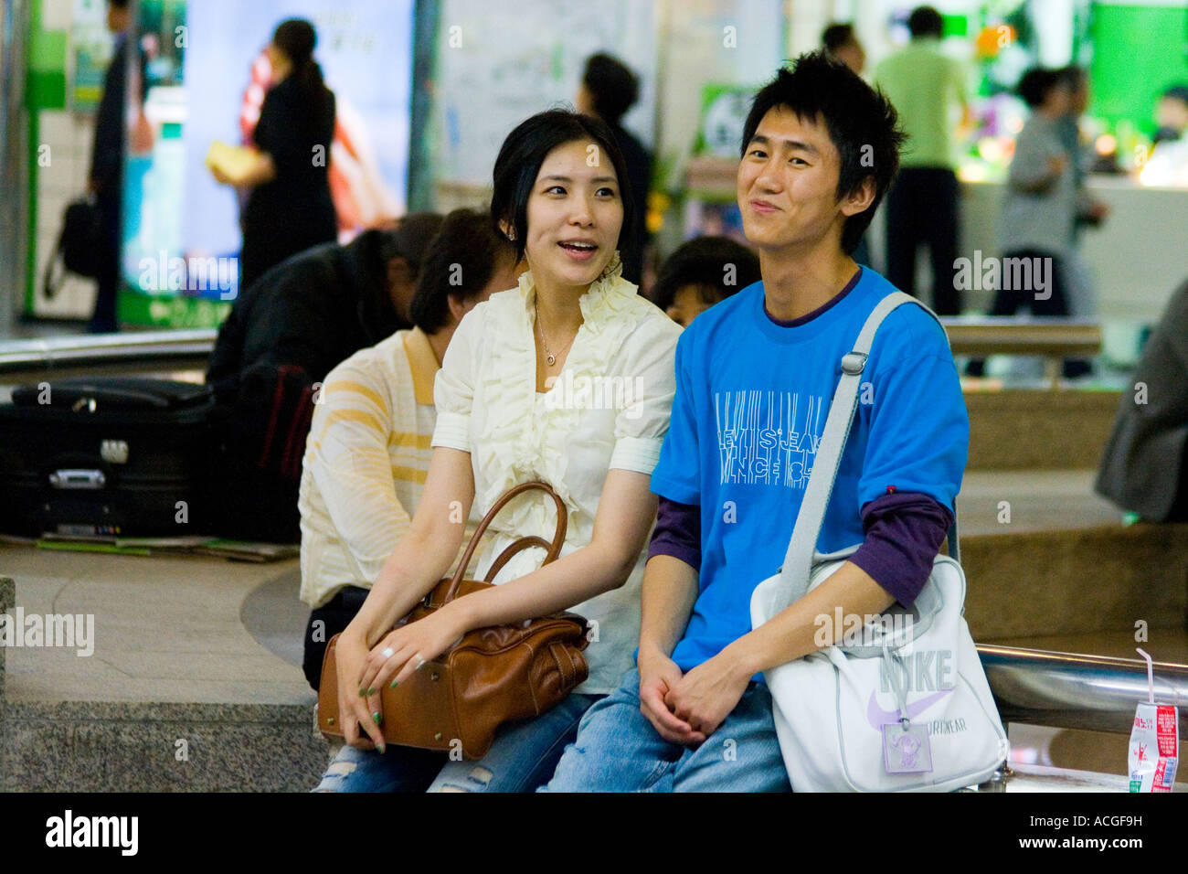 Young Korean Couple Sitting Sitting and Talking Together at a Mall Seoul South Korea Stock Photo