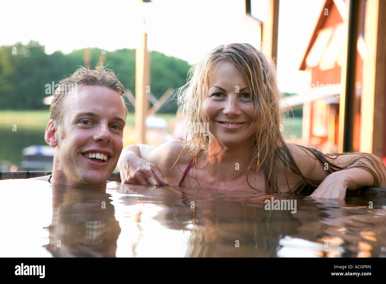A man and a woman bathing in a barrel outdoors. Stock Photo