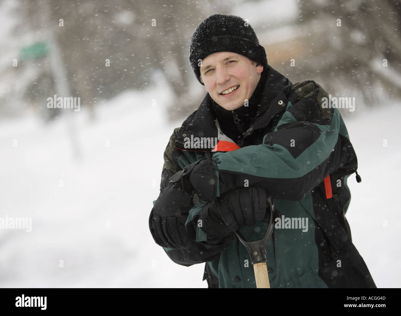 Man leaning on shovel in the snow Stock Photo