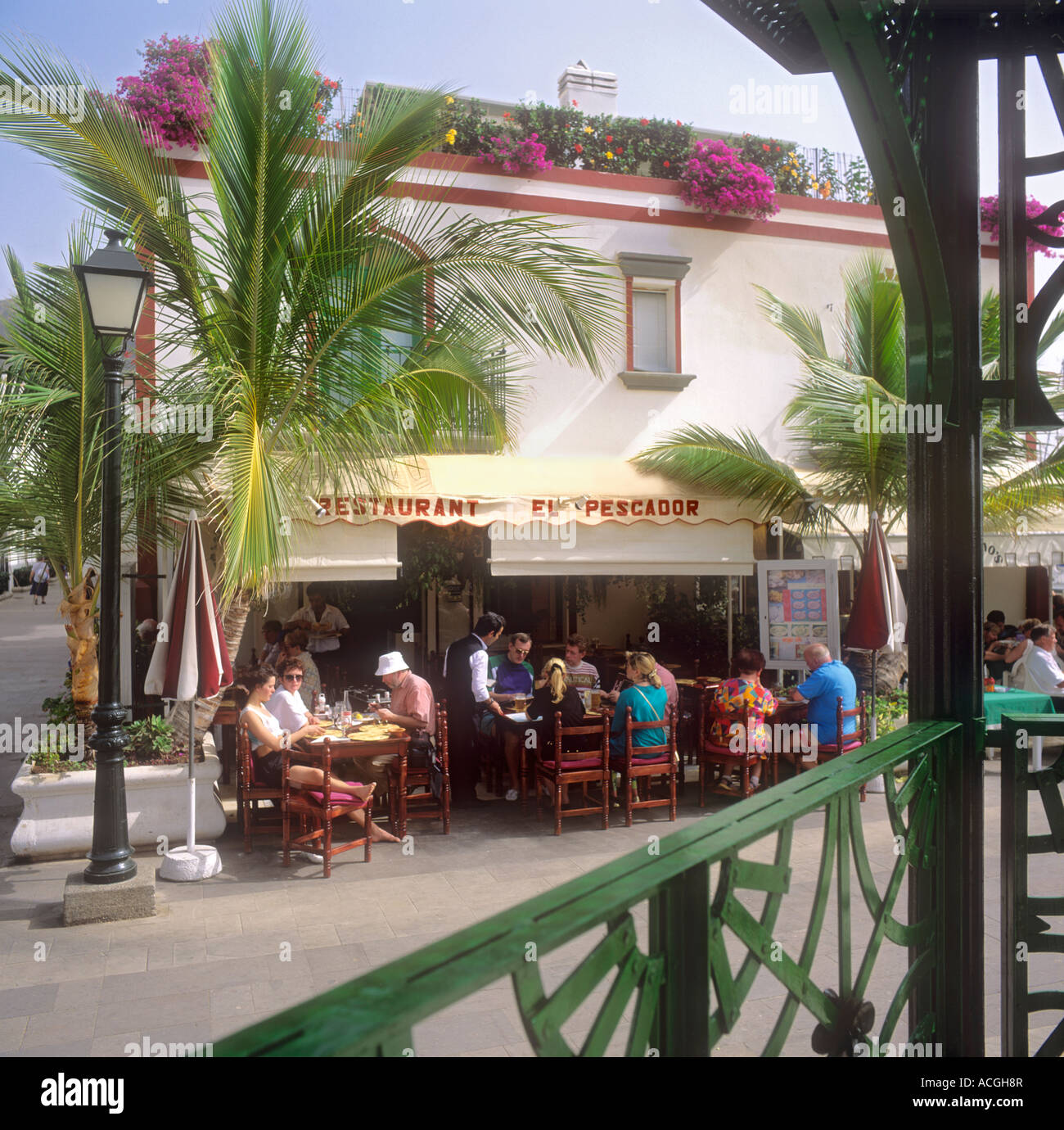 Waiter serving Spanish tapas on terrace of typical Puerto de Mogan