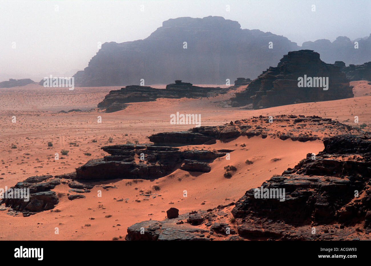 Red sand floor of the desert with rocky outcrops called Jebels in the distance Wadi Rum Jordan Stock Photo