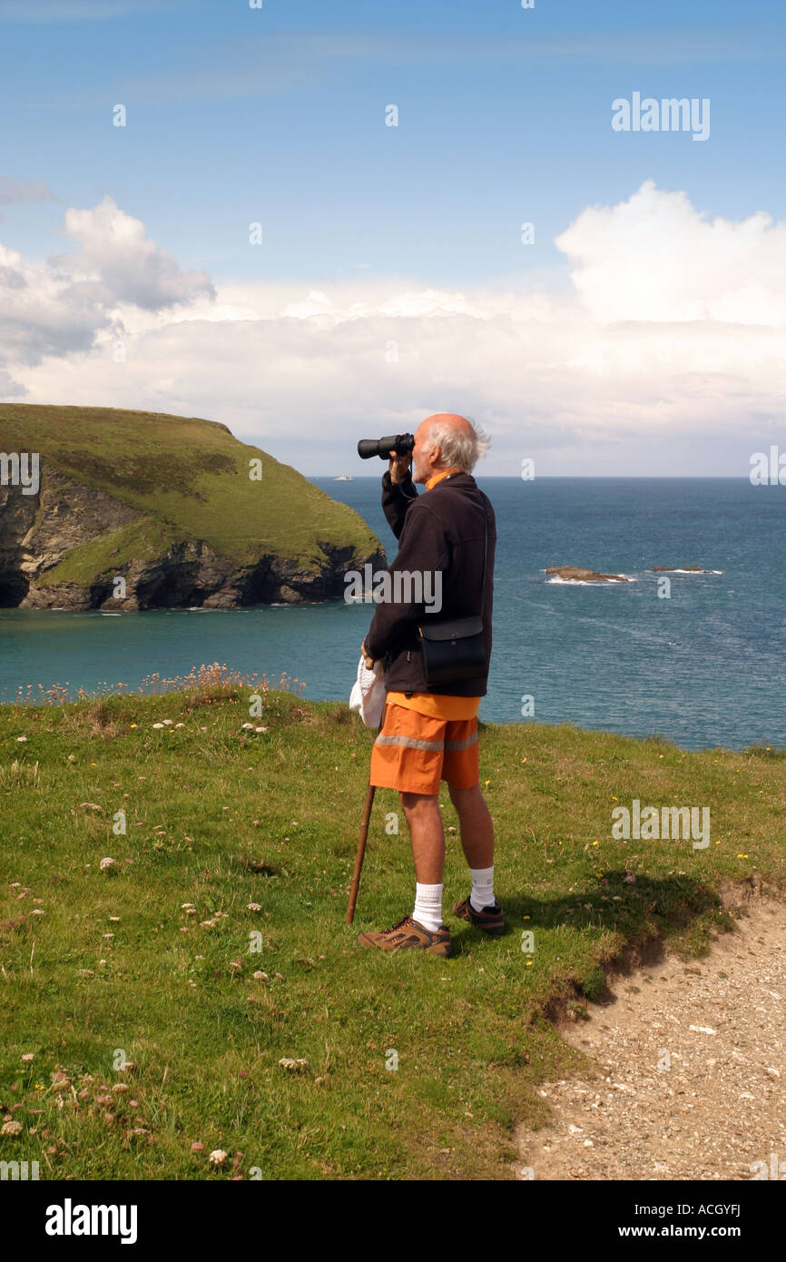 Elderly man using binoculars Lighthouse hill Portreath Cornwall UK Stock Photo