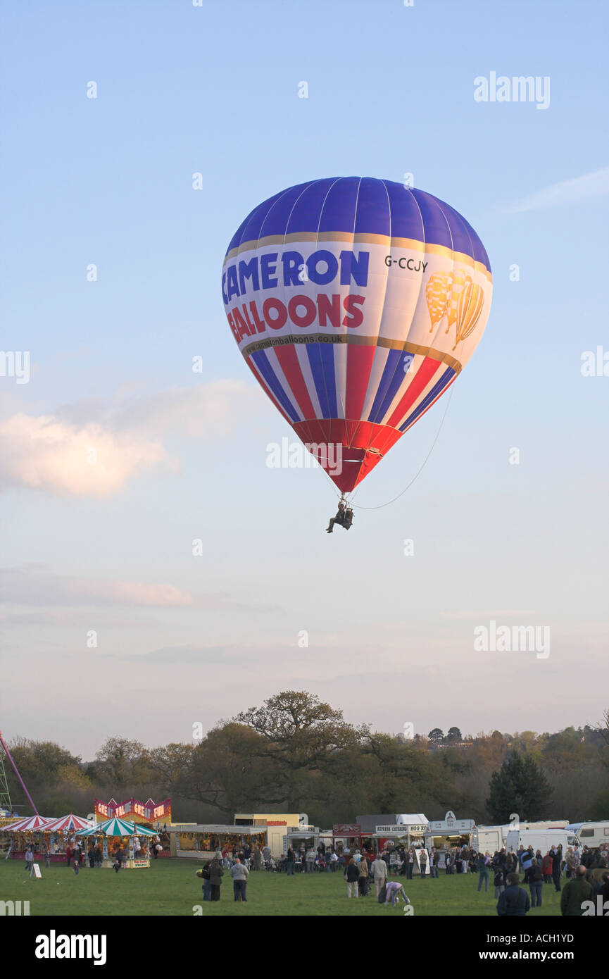 Colourful Cameron hot air balloon above fairground in evening light Stock Photo